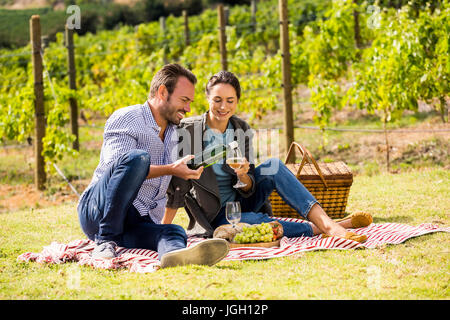 Man pouring wine from bottle in glass held by young woman at lawn Stock Photo