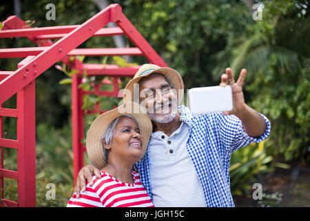 Happy senior couple taking selfie while standing in yard Stock Photo