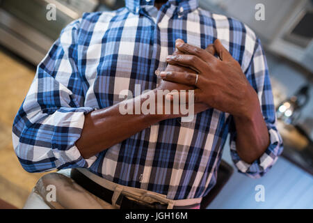 Midsection of man with hand on chest suffering from chest pain while standing at home Stock Photo