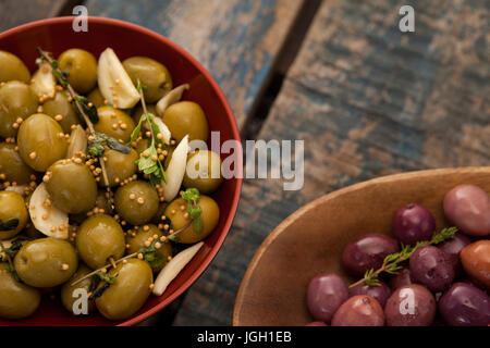 Cropped image of olives served in containers on wooden table Stock Photo