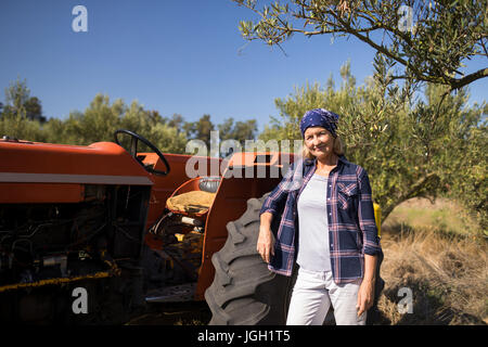 Portrait of confident woman standing near tractor in olive farm on a sunny day Stock Photo