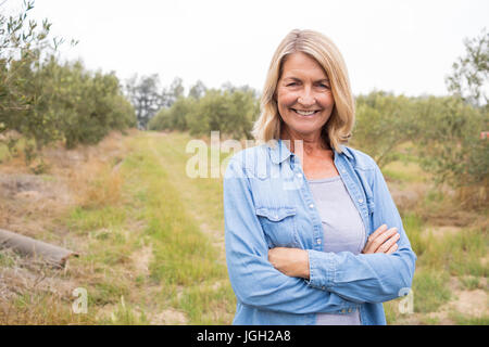 Portrait of happy woman standing with arms crossed in olive farm Stock Photo