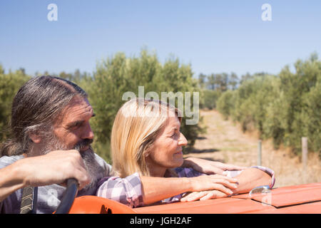 Thoughtful couple standing near tractor in olive farm on a sunny day Stock Photo