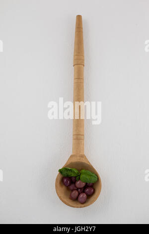 Overhead view of brown olives with herb in woden laddle on ladle Stock Photo