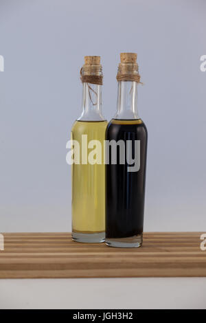 Olive oil in bottles on table against wall Stock Photo