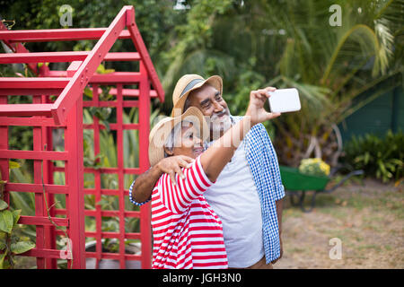 Smiling senior couple taking selfie while standing in yard Stock Photo