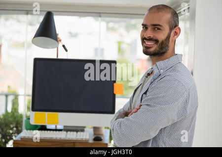 Side view portrait of designer with arms crossed standing in office Stock Photo