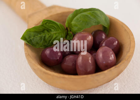 Close up of brown olives with herb in laddle on ladle Stock Photo