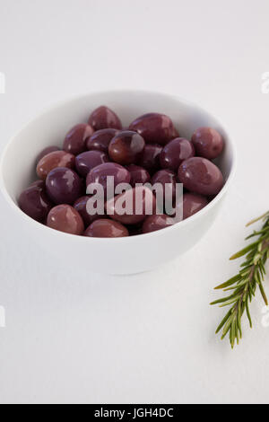Close up of brown olives by herb on table Stock Photo