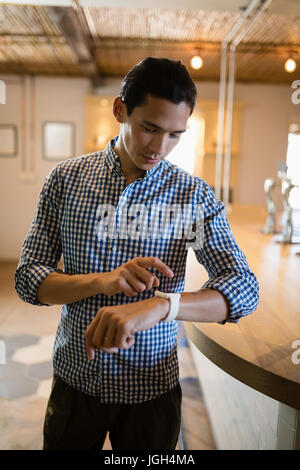 Man operating smartwatch at counter in restaurant Stock Photo