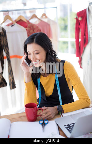 Smiling female designer talking on mobile phone in office Stock Photo