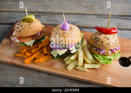 High angle view of various burgers on cutting board at table against wall Stock Photo