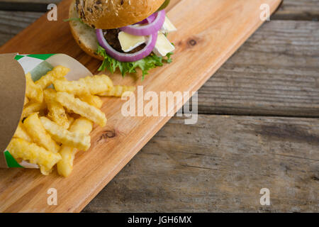High angle view French fries in box by burger on cutting board at table Stock Photo