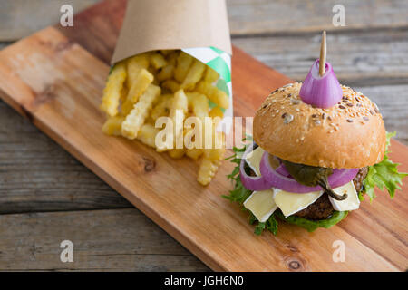 High angle view of burger by French fries in box on cutting board at table against wall Stock Photo