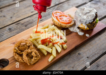 High angle view of bottle pouring sauce on French fries by burger ingredients Stock Photo