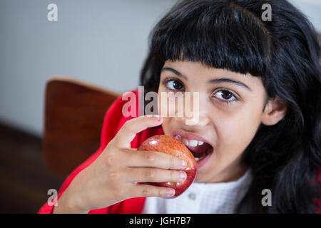 High angle portrait of girl eating fresh apple at home Stock Photo