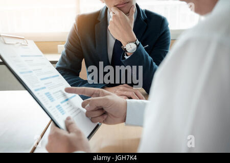 business man interviewer looking skeptical while listening to an asian female interview Stock Photo