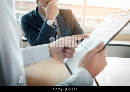 business man interviewer looking skeptical while listening to an asian female interview Stock Photo