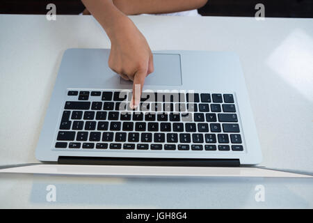 High angle view of girl pressing key on laptop at kitchen counter Stock Photo