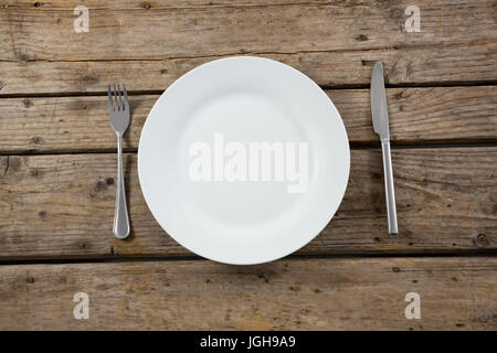 Overhead view of empty plate with cutlery on wooden table Stock Photo