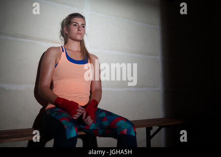 Thoughtful woman relaxing on bench in fitness studio Stock Photo