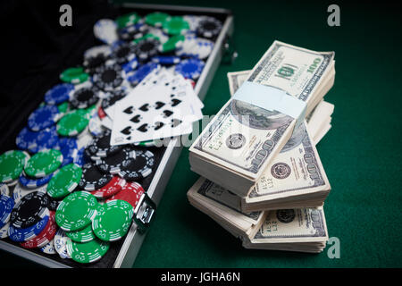 Bundle of US dollars, playing cards and casino chips on poker table in casino Stock Photo