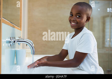 Portrait of smiling boy washing hands in sink at bathroom Stock Photo