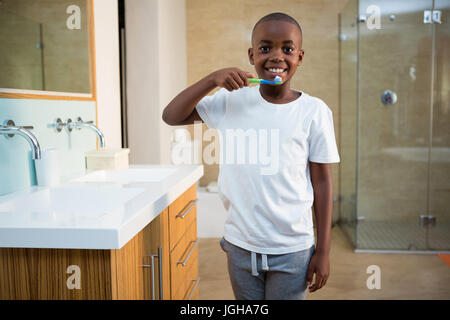 Portrait of smiling boy with toothbrush standing by sinkin bathroom Stock Photo