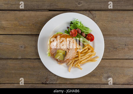 Overhead of hamburger, french fries and salad in plate on wooden table Stock Photo