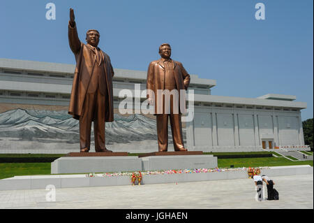 08.08.2012, Pyongyang, North Korea, Asia - Two North Koreans bow in front of the giant bronze statues of the late leaders Kim Il Sung and Kim Jong Il  Stock Photo