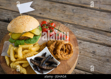 High angle view of ingredients with burger on cutting board at wooden table Stock Photo