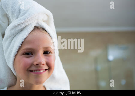 Portrait of smiling girl with hair wrapped in towel in bathroom Stock Photo