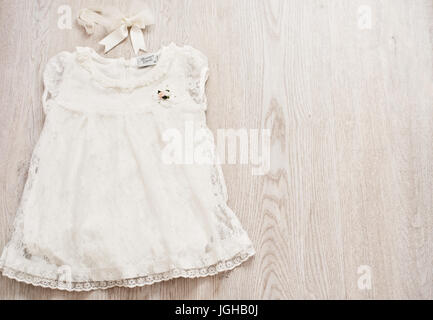 Vintage Baby White Lace Dress and Bow Headband on a Light Gray Wodden Background. Top View, Copy Space Stock Photo