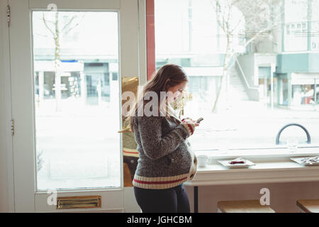 Pregnant woman using mobile phone in the restaurant Stock Photo