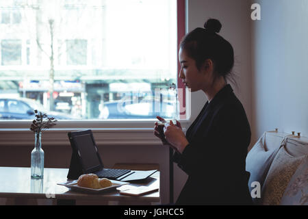 Woman having coffee while using digital tablet in the restaurant Stock Photo