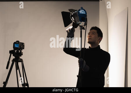 Concentrated male photographer adjusting light in studio Stock Photo