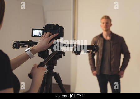 Cropped image of female photographer photographing male model against backdrop at studio Stock Photo