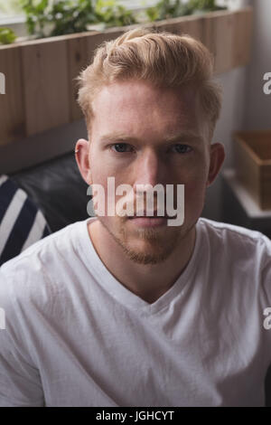 Portrait of young man sitting on sofa at home Stock Photo