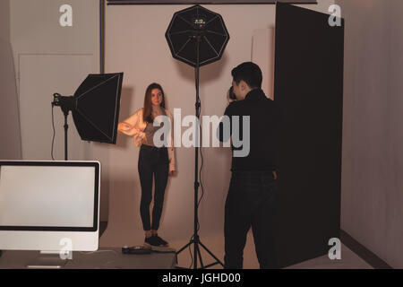 Photographer photographing female model standing at film studio Stock Photo