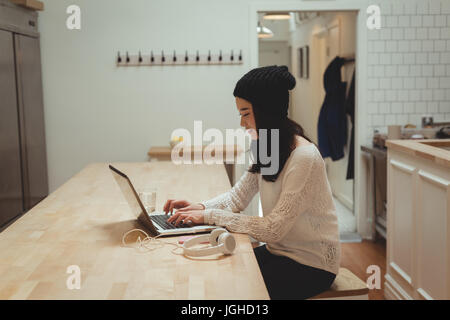 Beautiful woman using laptop in kitchen at home Stock Photo