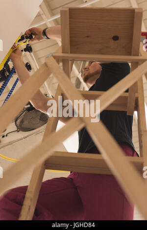 Low angle view of man on wooden ladder adjusting backdrop at studio Stock Photo