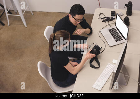 High angle view of photographer with assistant looking into camera by laptop in studio Stock Photo