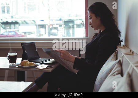 Beautiful woman reading newspaper in restaurant Stock Photo