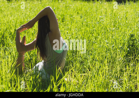 Woman doing stretching exercise in field on a sunny day Stock Photo