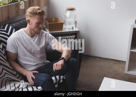 Young man checking time while sitting on sofa at home Stock Photo