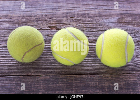 Three used tennis balls on wooden background Stock Photo