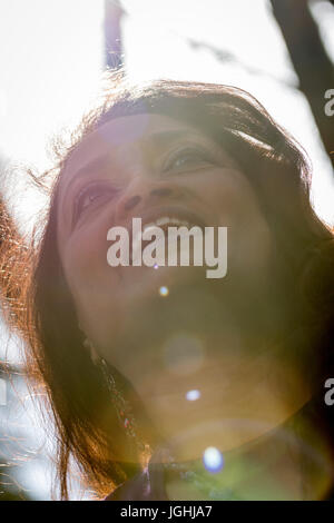 Middle aged smiling woman with smile shot from below with severe lens flare. Big smile shows perfect teeth and lively look in her eyes. Stock Photo