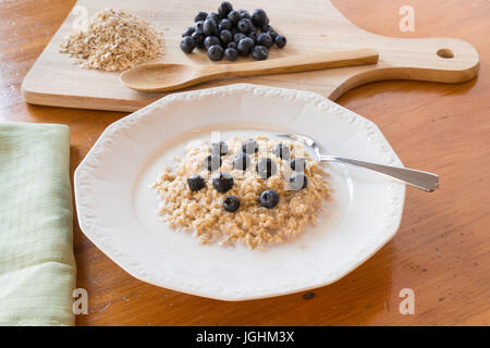 Oatmeal with blueberries and milk in a white bowl Stock Photo