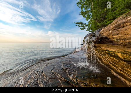 Elliot Falls spills over sculpted rock at Pictured Rocks National Lakeshore in Munising Michigan. This little waterfall is on Miner's Beach. Stock Photo