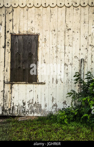 Abandoned white painted exterior barn wall with boarded windows Stock Photo